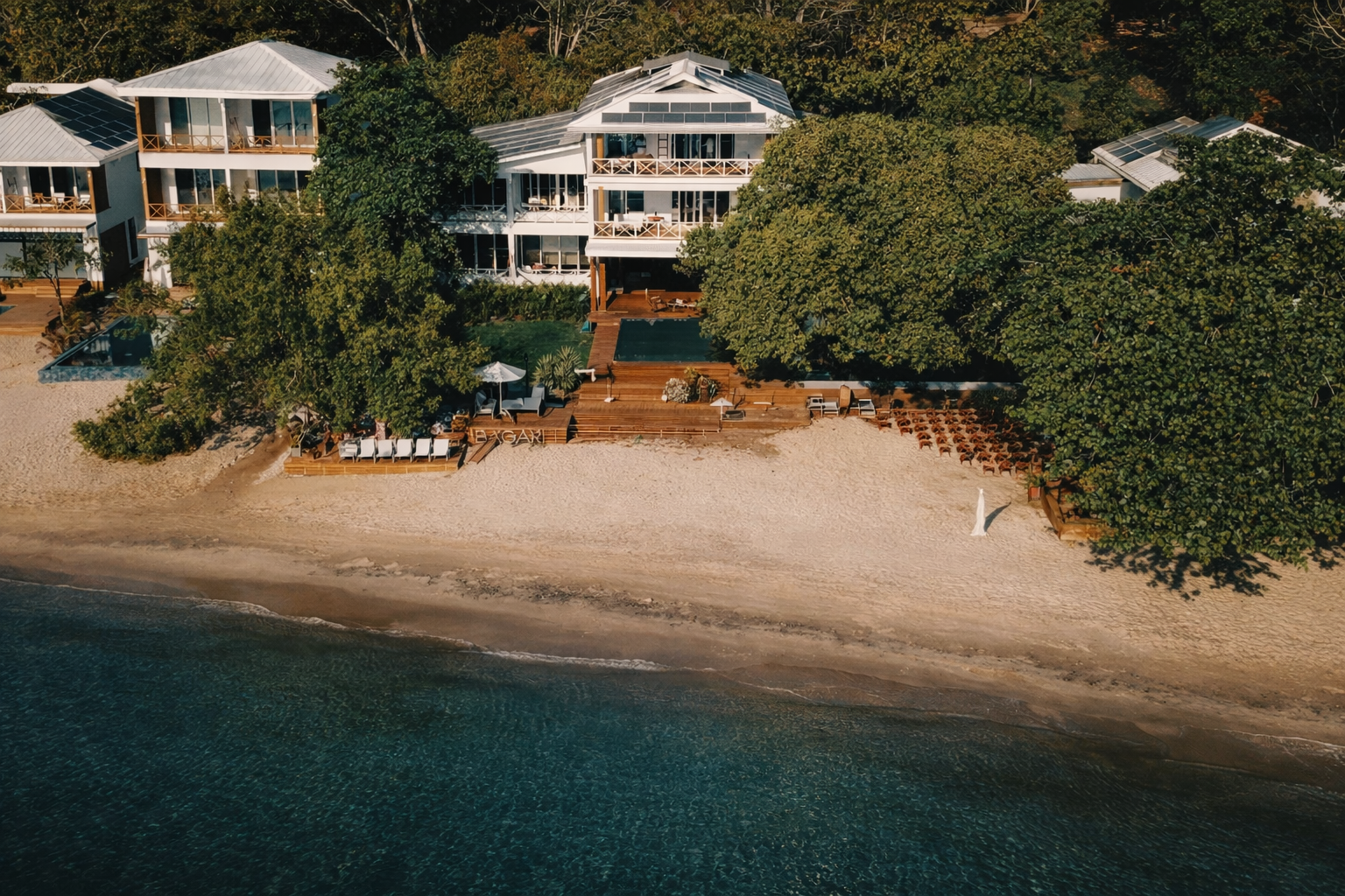 Vista aérea de resort frente al mar con ceremonia en la playa al atardecer