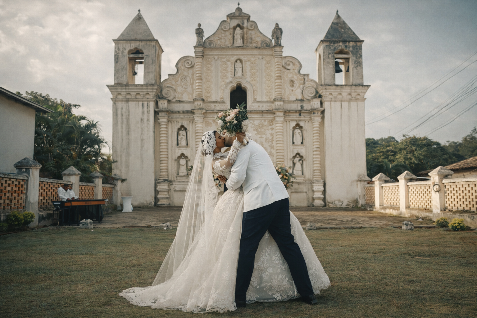 Novios besándose frente a una iglesia colonial al atardecer